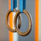 Soft focus of steady gymnastic rings hanging on blue belts during training in gym