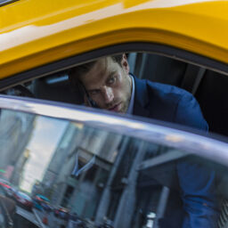 Businessman sitting in taxi, using smart phone