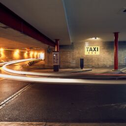 Taxi stand sign and underground parking in station.